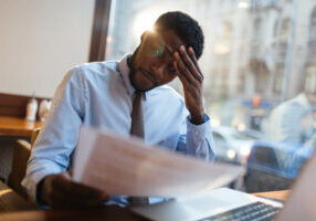 focused african american office manager sitting at cafe table with laptop reading impo SBI 324310474 2